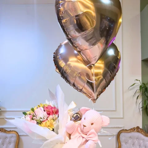 Ramalhete de flores com boneco de pano listrado e dois balões flutuando