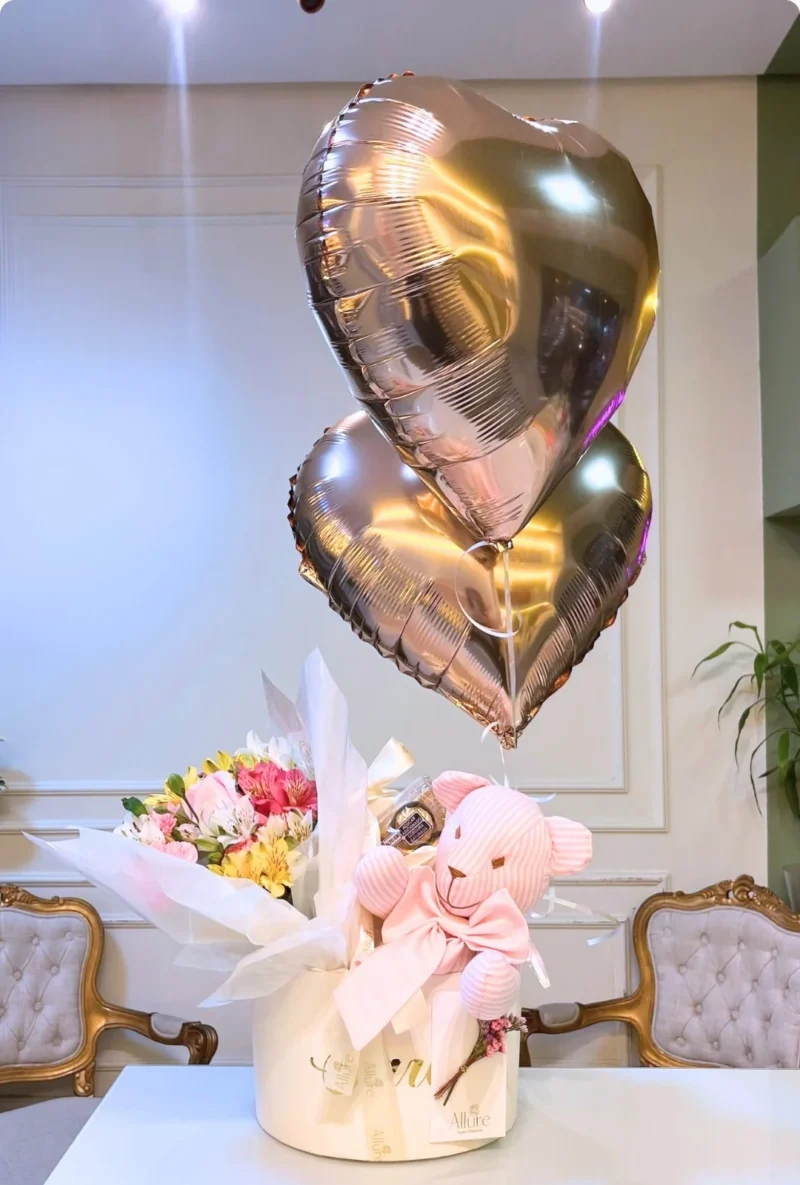 Ramalhete de flores com boneco de pano listrado e dois balões flutuando